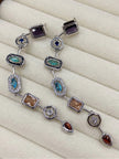 Flat overhead shot of the earring pair in a cream jewellery tray showing the full articulated chain link drop and all geometric stone stations