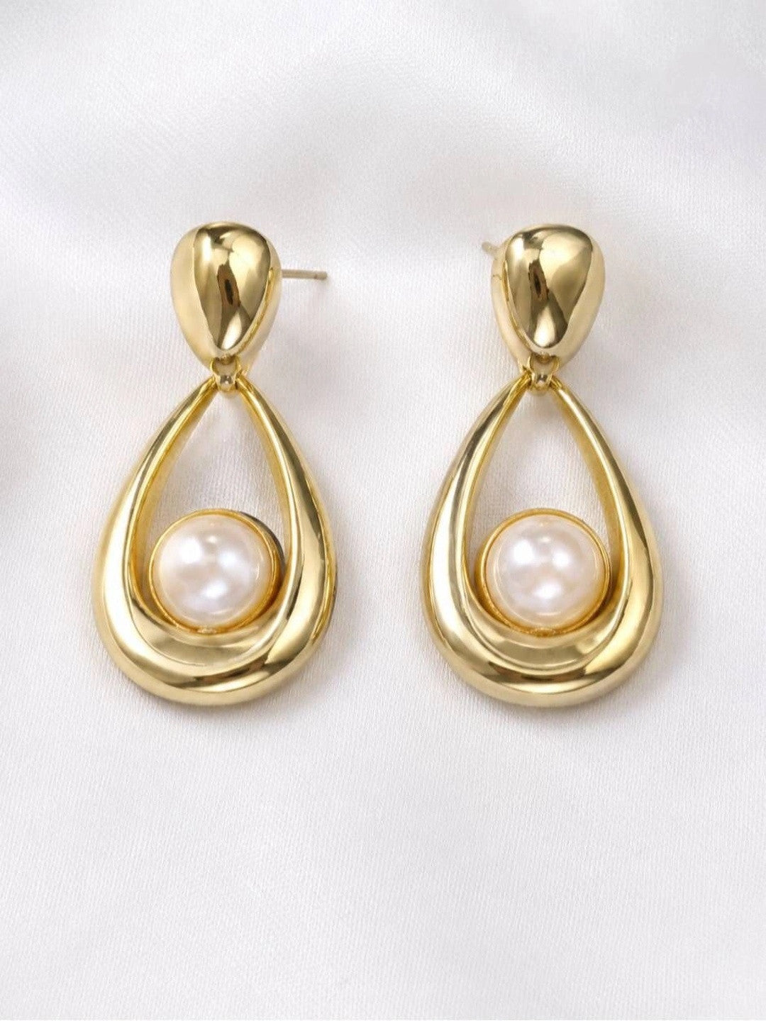 Both gold teardrop pearl drop earrings laid flat side by side on white fabric, front-facing