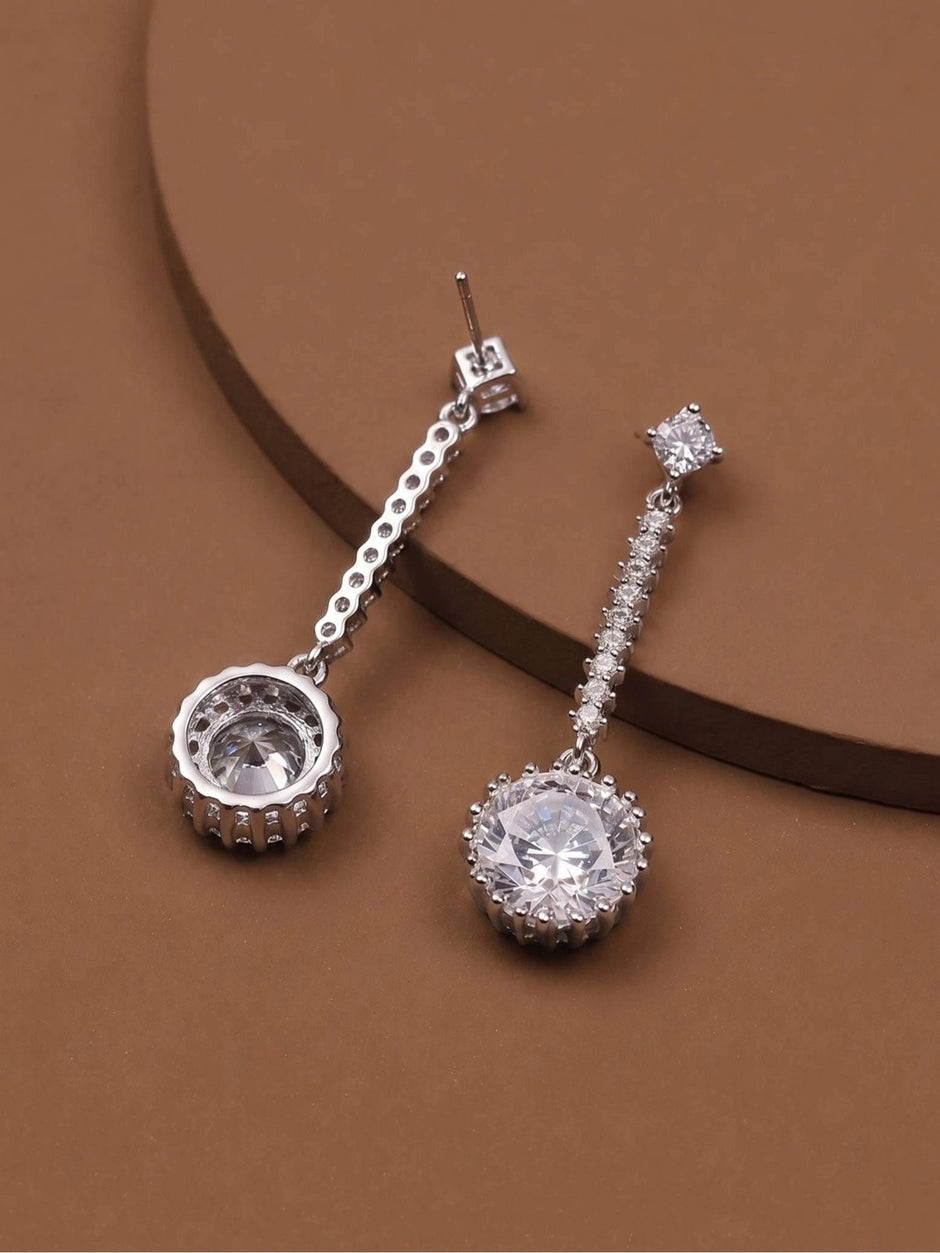 Silver-tone CZ halo drop earrings displayed side by side on a brown surface, showing front and back angles