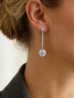 Silver CZ halo long drop earring worn on a woman's ear with hair swept up