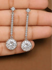 Close-up of silver CZ halo drop earrings held in a woman's palm showing stone detail