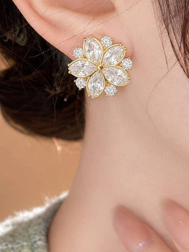 Gold-plated cubic zirconia floral stud earring worn on a woman's ear, close-up lifestyle view