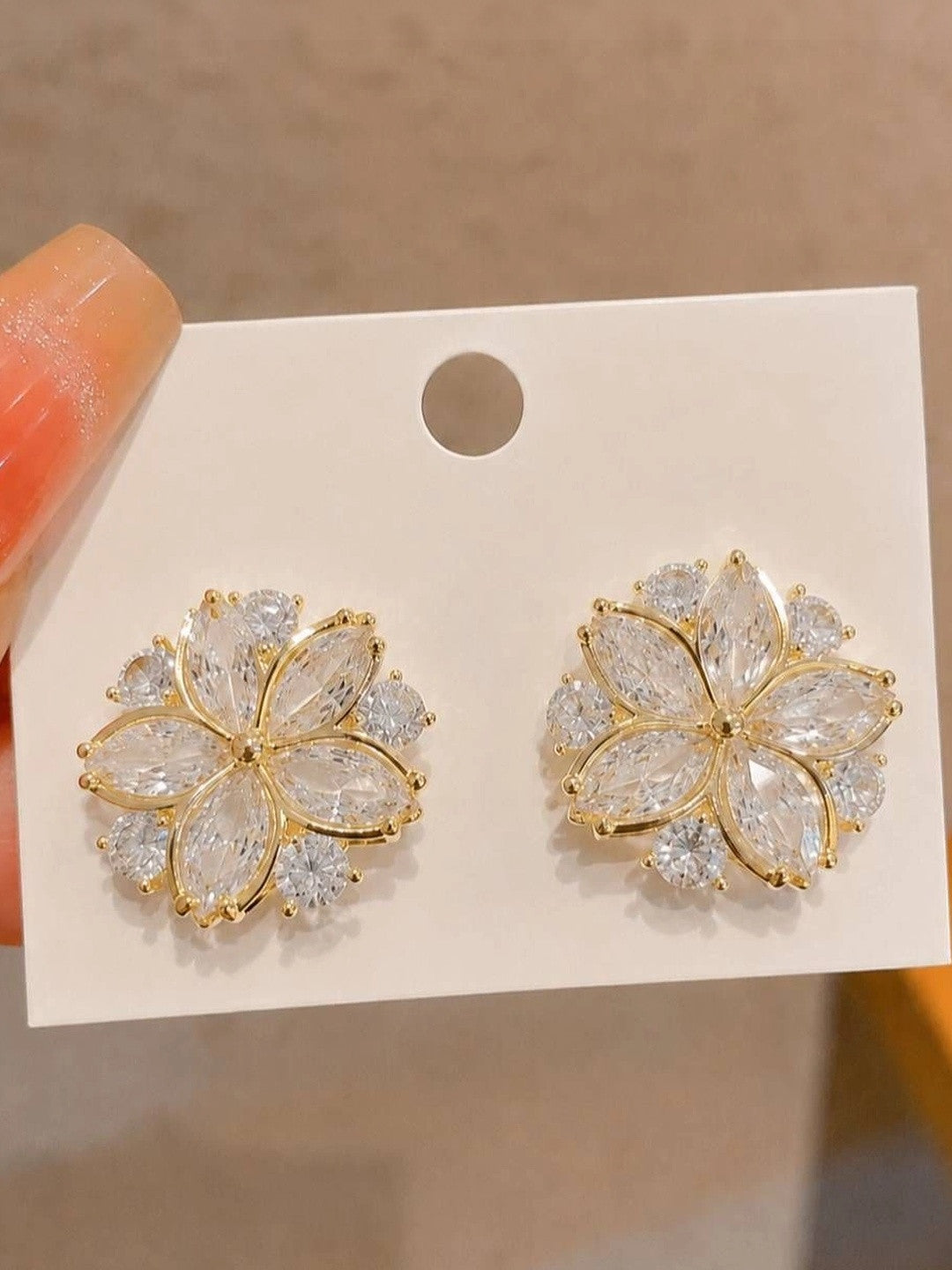 Pair of gold-plated cubic zirconia floral stud earrings displayed on white jewellery card