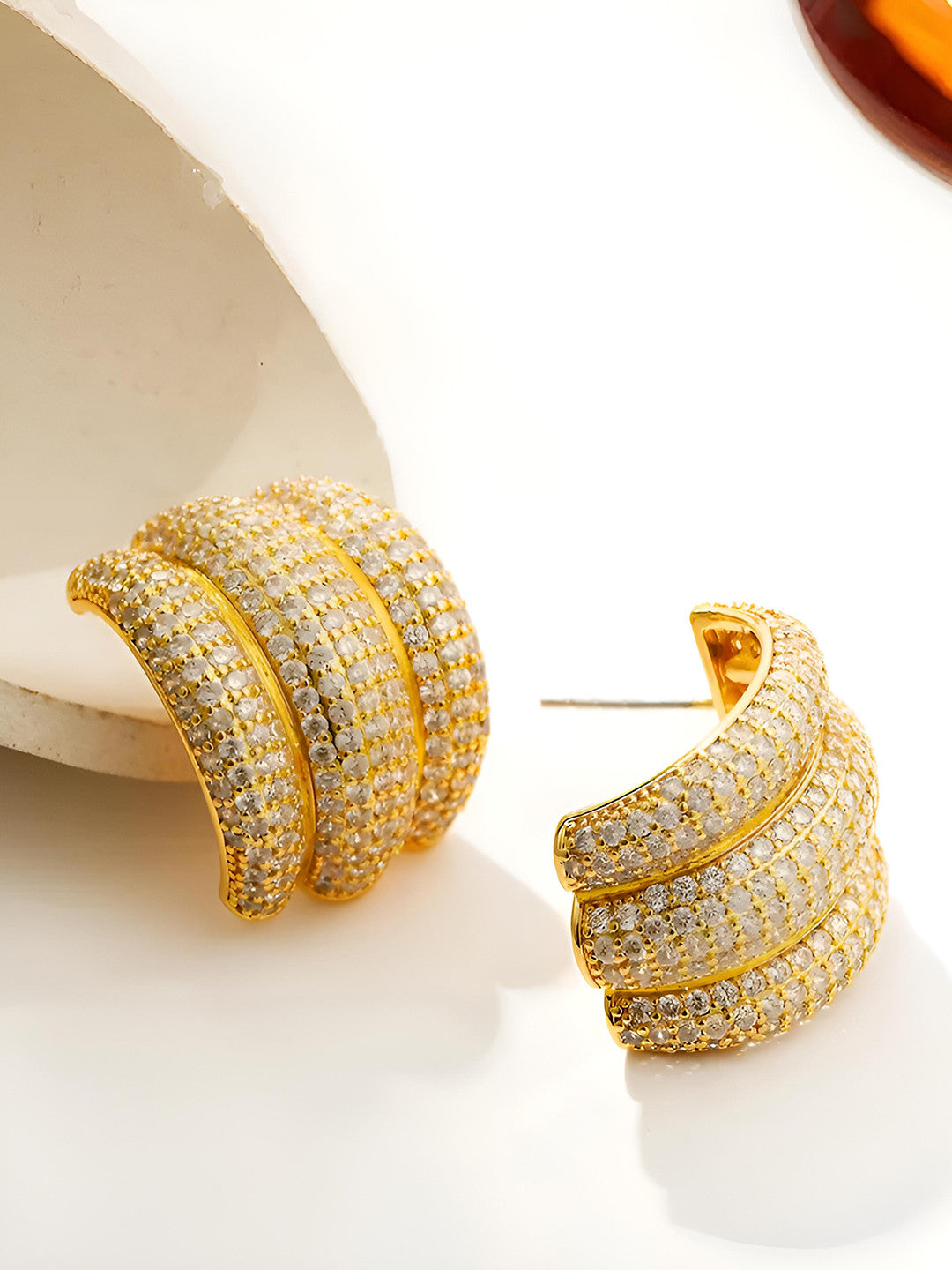Close-up of gold-plated CZ pave hoop earrings showing post-back fitting and triple-band detail