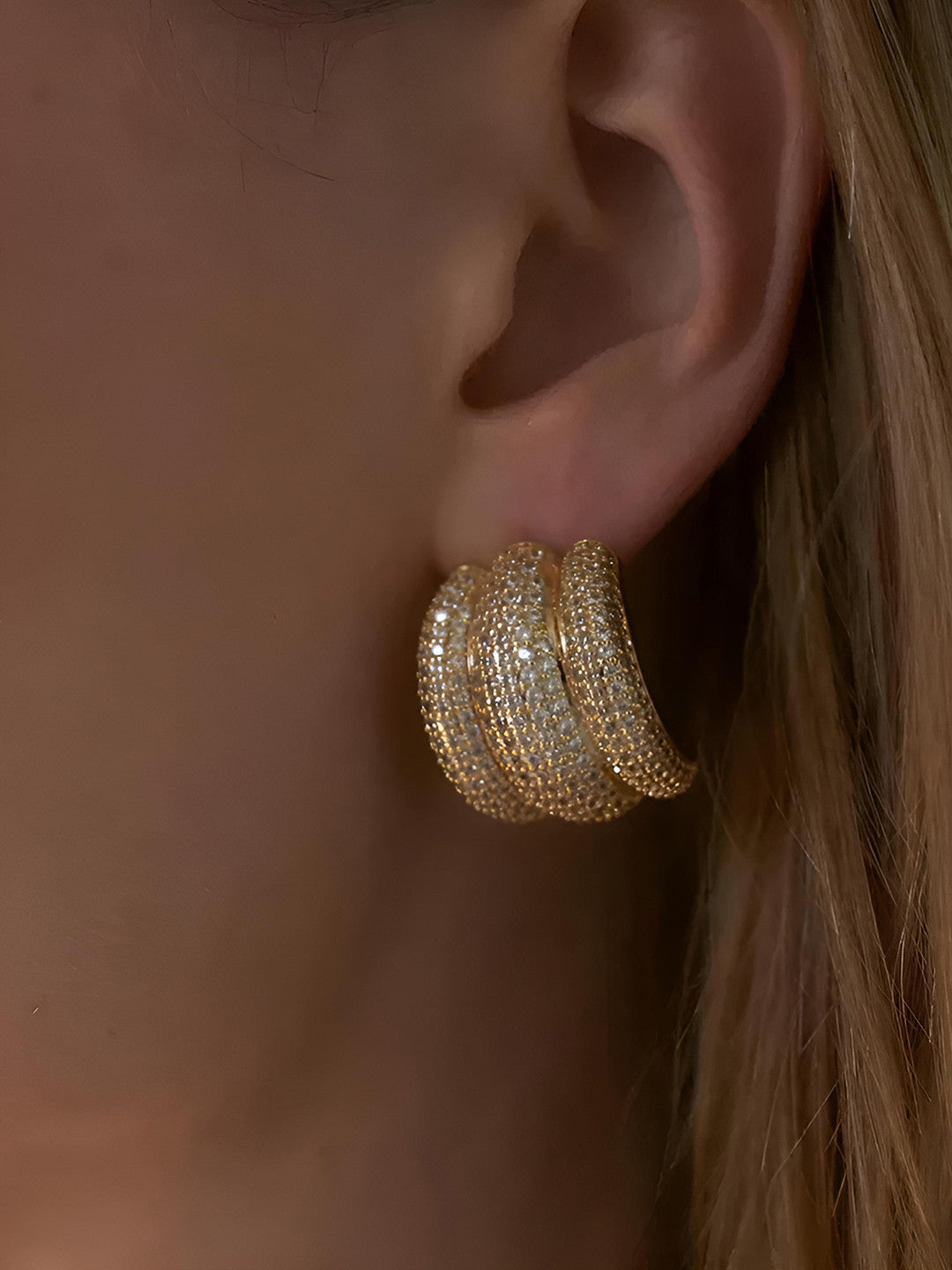 Gold-plated chunky cubic zirconia hoop earring worn on a model's ear, side profile view