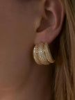 Gold-plated chunky cubic zirconia hoop earring worn on a model's ear, side profile view