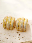 Both gold-plated CZ chunky hoop earrings placed side by side on a textured stone surface