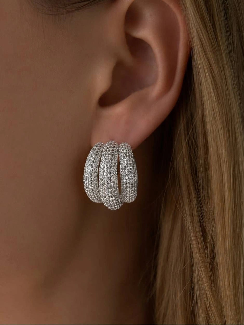 Close-up of silver cubic zirconia triple hoop earring worn on a model's ear