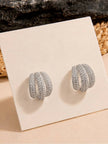 Pair of silver triple hoop earrings displayed upright on a cream jewellery card against a textured backdrop