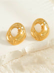 Pair of gold-plated chunky hollow oval stud earrings displayed flat on white surface with fabric