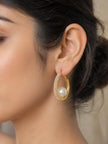 Close-up of gold CZ pearl hoop earring worn on a woman's ear with dark upswept hair