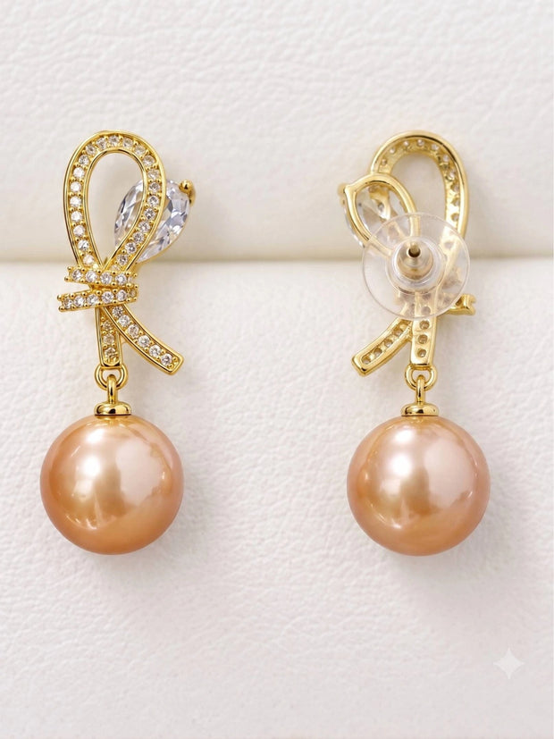 Front and back view of gold-plated pearl drop earrings with butterfly clasp on display cushion