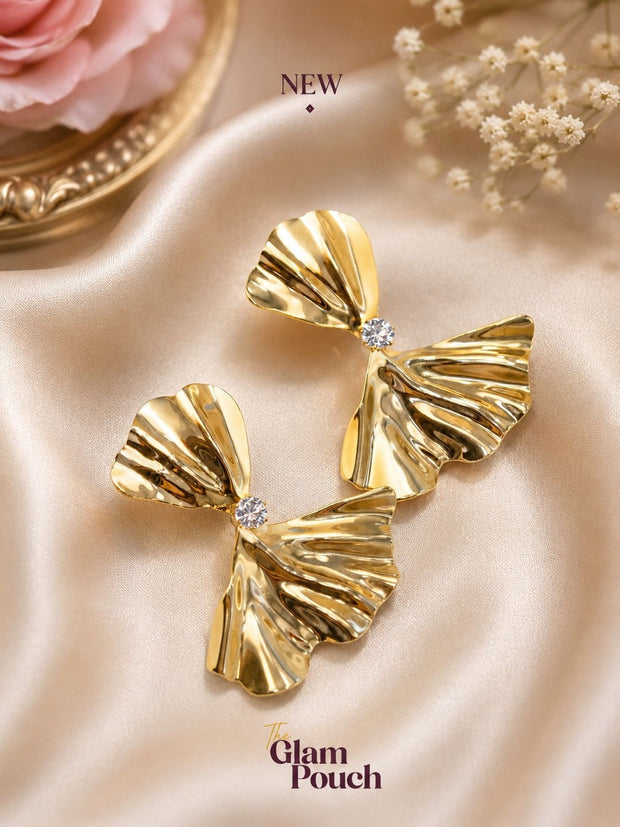 Pair of gold-plated ridged bow earrings with crystal centre on champagne satin fabric