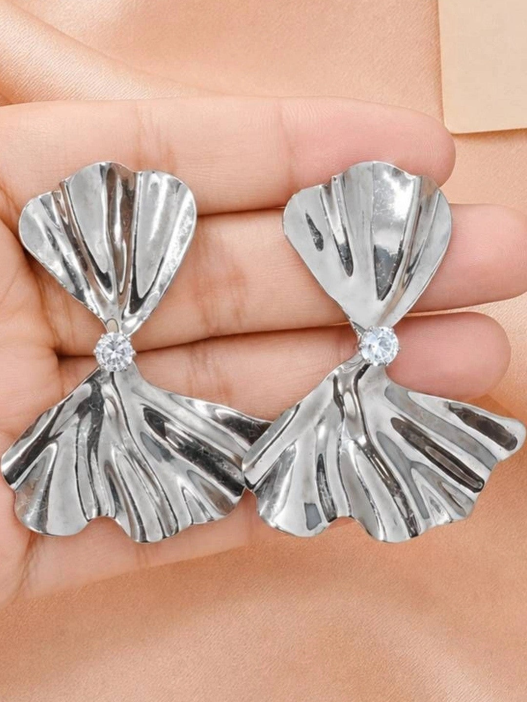 Both silver bow drop earrings held in a palm showing front face and cubic zirconia centre