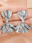 Both silver bow drop earrings held in a palm showing front face and cubic zirconia centre