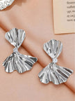 Pair of silver bow drop earrings side by side on pink fabric showing ridged fan-shaped panels