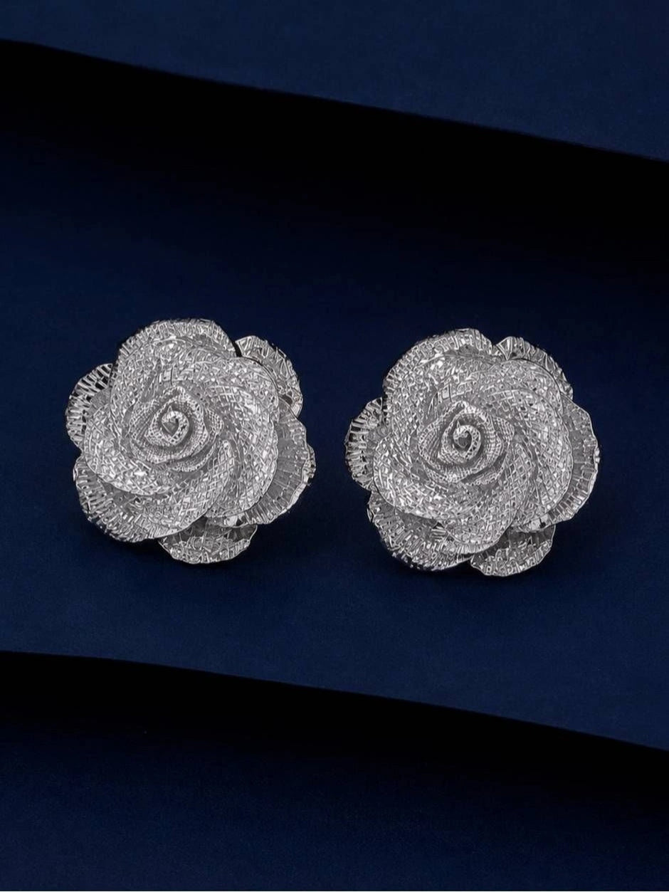 Pair of silver-finish rose stud earrings with textured mesh petals on a navy background