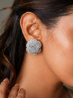 Silver rose stud earring worn on a woman's ear showing size and fit