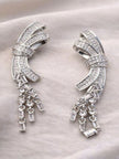 Pair of silver-toned CZ bow drop earrings laid flat on a cream fabric background