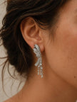 Silver CZ bow drop earring worn on a woman's ear showing full length and drape