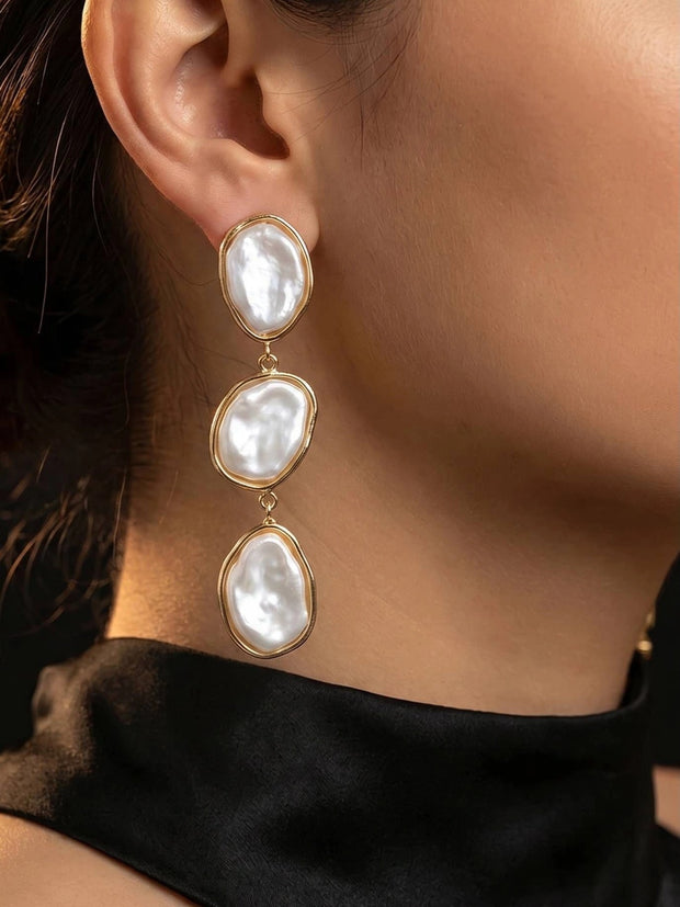 Gold-plated triple baroque faux pearl drop earring worn on a woman's ear against a black outfit