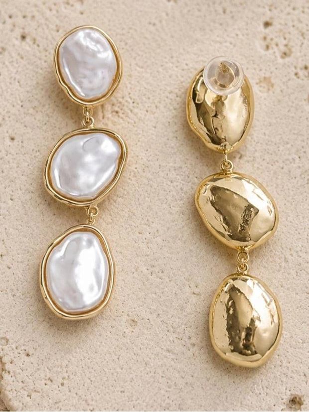 Front and back view of gold-plated triple baroque pearl drop earrings on a stone surface showing post closure