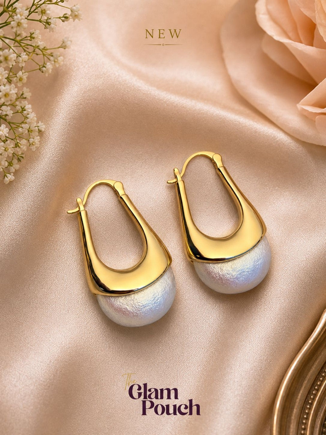 Pair of gold vermeil elongated hoop earrings with ivory pearl drops on peach satin fabric