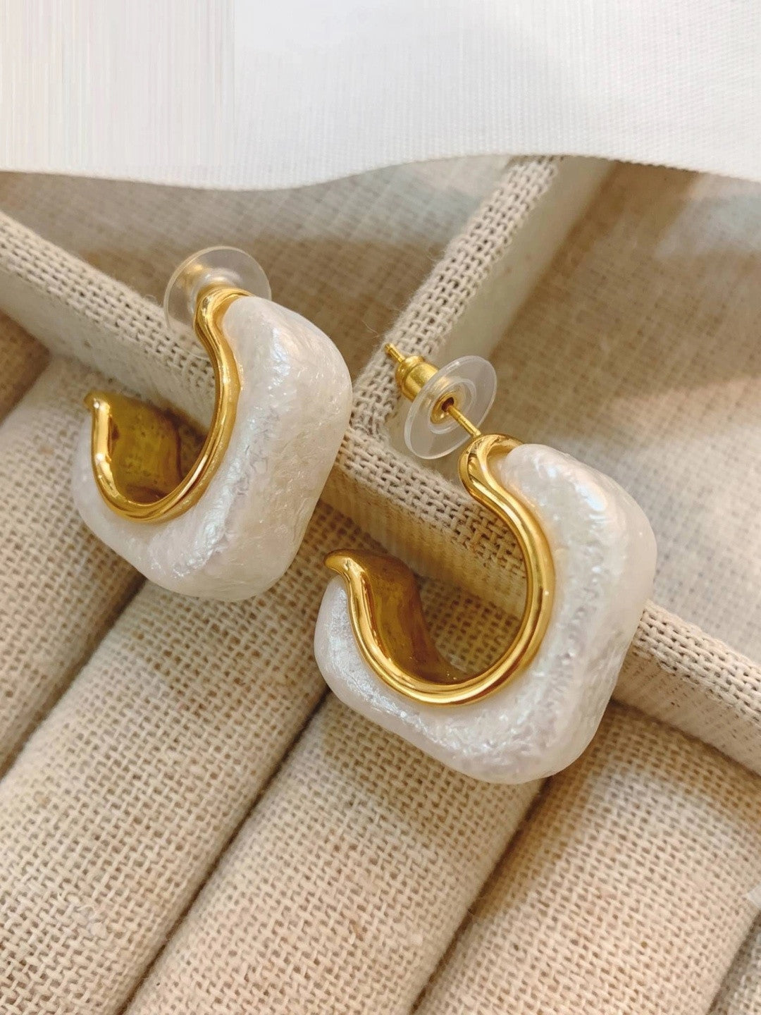 Close-up side view of pearl resin hoops showing gold inner hoop and rubber push-back stoppers