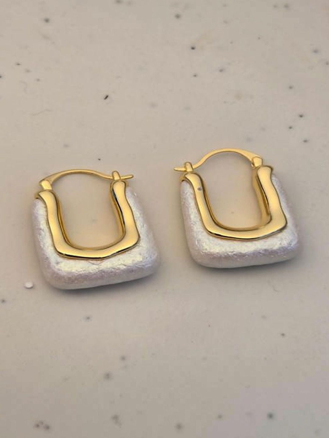 Front-facing view of both baroque pearl hoop earrings laid flat on a marble-effect surface showing full rectangular silhouette