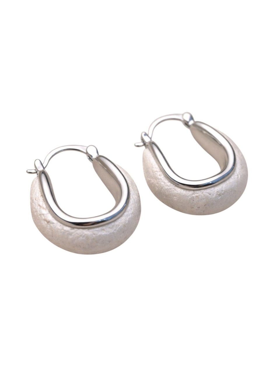 Front-facing pair of silver oval hoop earrings with polished frame and matte composite base on white background