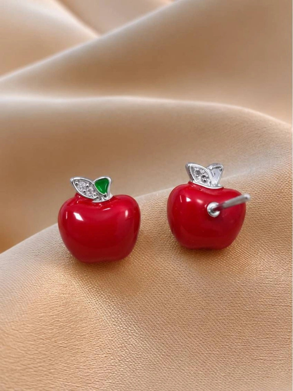 Close-up of red apple stud earrings showing push-back post and silver leaf setting on skin