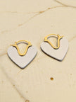 Two-tone heart hoop earrings laid flat on cream fabric showing gold hoop detail and silver heart front