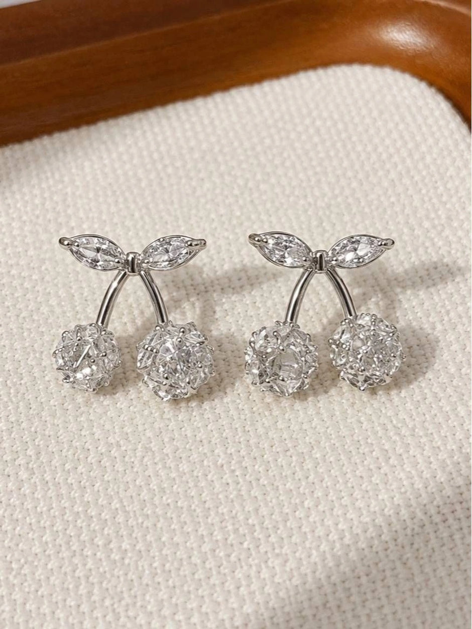 Pair of silver-finish cherry stud earrings with zirconia crystal spheres and marquise leaf accents on cream fabric