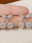 Close-up of two pairs of silver cherry stud earrings held in hand showing zirconia stone arrangement