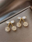 Pair of gold-plated crystal cherry stud earrings laid flat on taupe satin fabric showing both pieces side by side