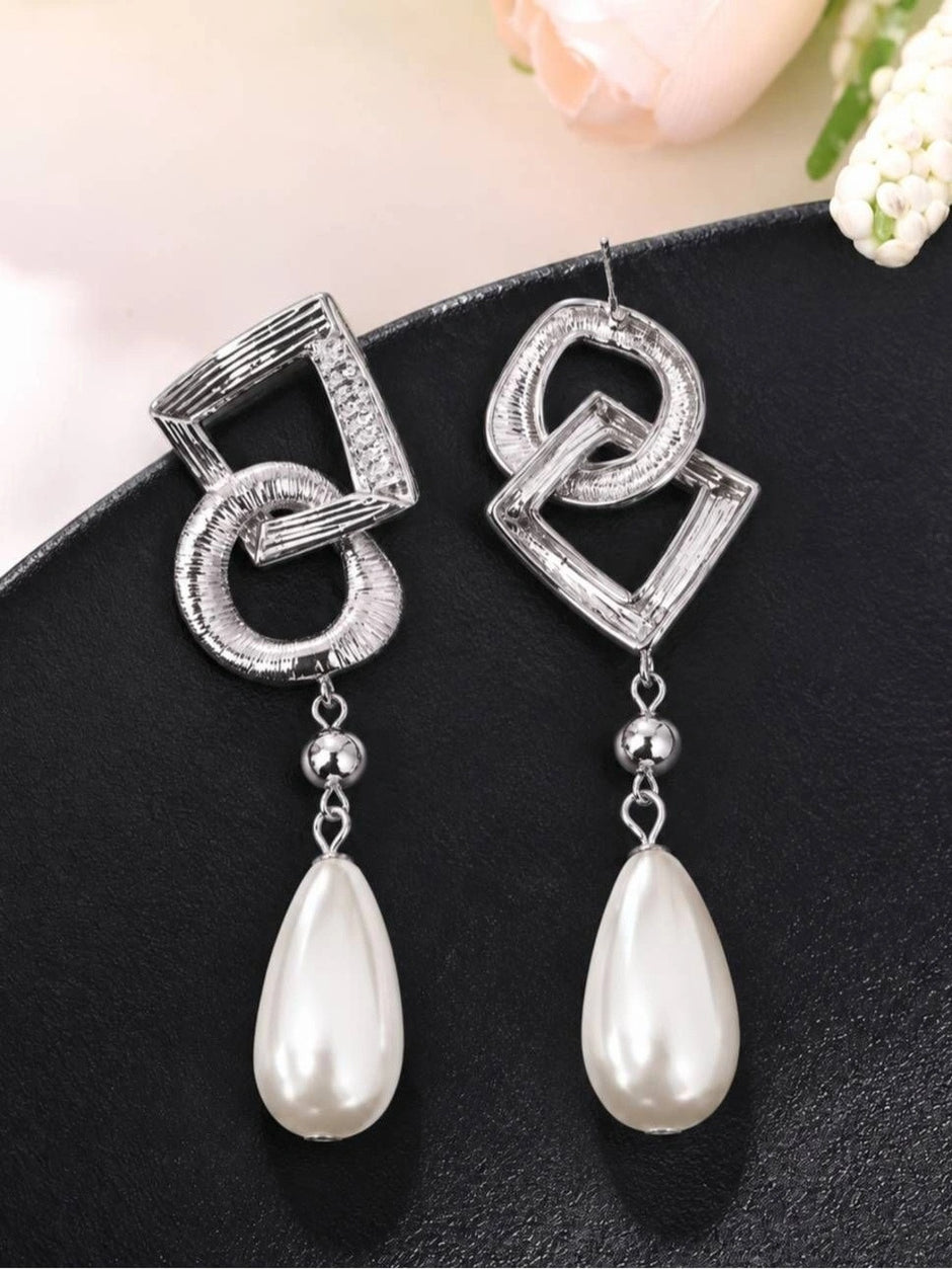 Two silver geometric drop earrings showing brushed ridged texture and pearl drops with silver ball connectors