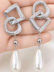 Both silver geometric pearl drop earrings displayed on a flat palm showing full front design detail