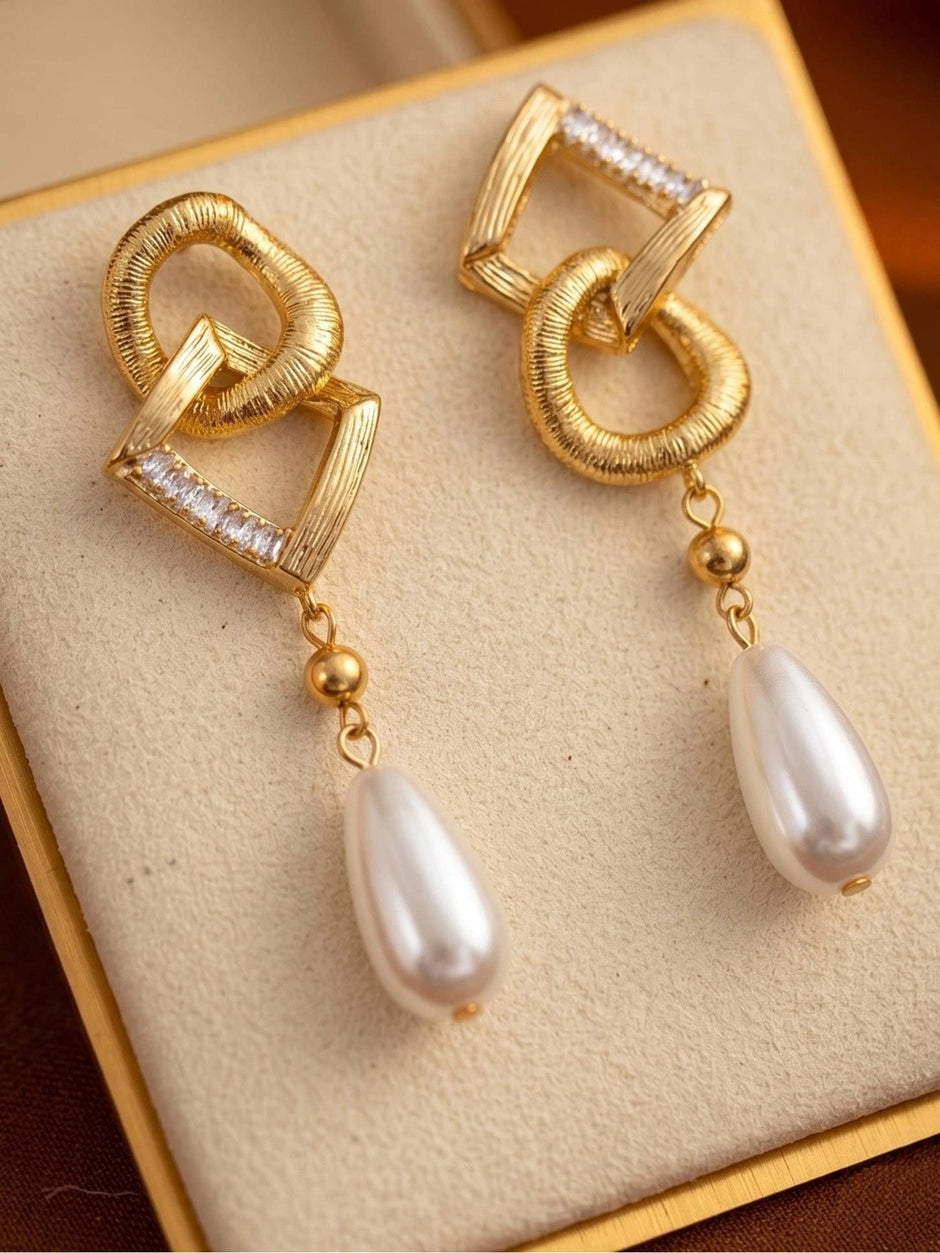 Gold-plated geometric pearl drop earrings displayed upright in a cream jewellery gift box