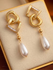 Gold-plated geometric pearl drop earrings displayed upright in a cream jewellery gift box