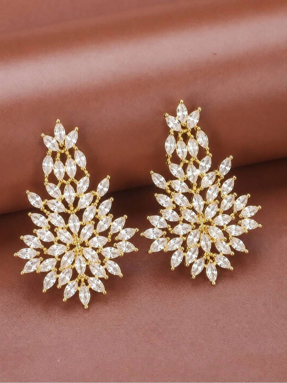 Pair of gold-plated marquise cubic zirconia floral drop earrings laid flat on a mauve surface