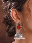 Close-up side profile of oxidised silver carnelian jhumka earring worn on a model's ear, showing pearl bead drop