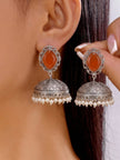 Model holding oxidised silver jhumka earring pair near her ear, showing scale and pearl fringe detail clearly