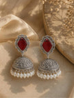 Pair of oxidised silver jhumka earrings with red stone studs and white pearl drop fringe on a cream fabric background