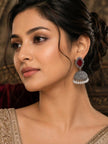 Woman wearing oxidised silver jhumka earring with red stone and pearl drops styled with an embroidered beige saree and updo hairstyle