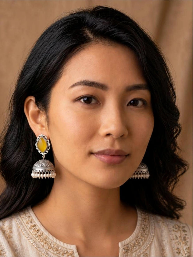 Model wearing oxidised silver yellow stone jhumka earrings paired with an ivory embroidered kurta