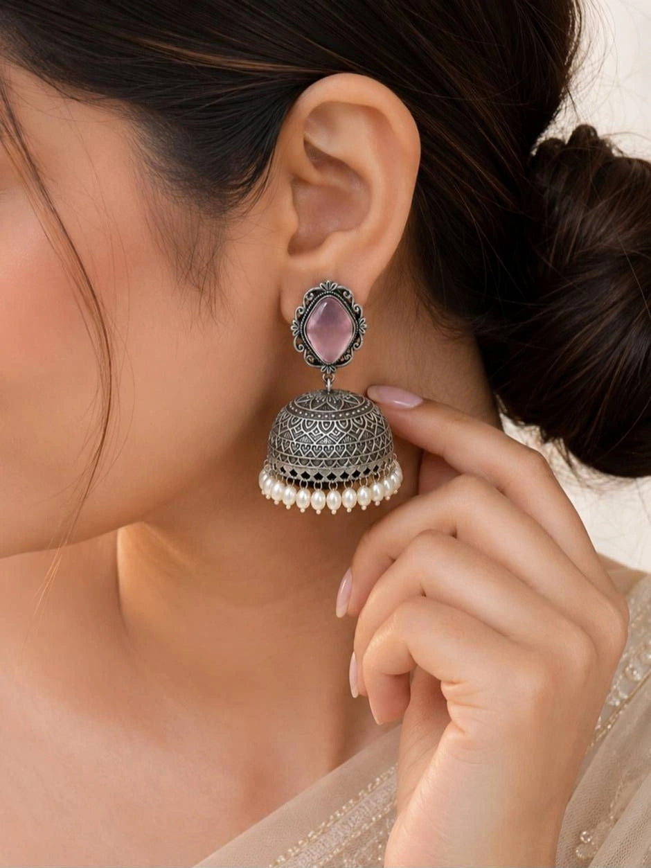 Close-up of oxidised silver jhumka with engraved dome and pearl drops worn on a woman's ear