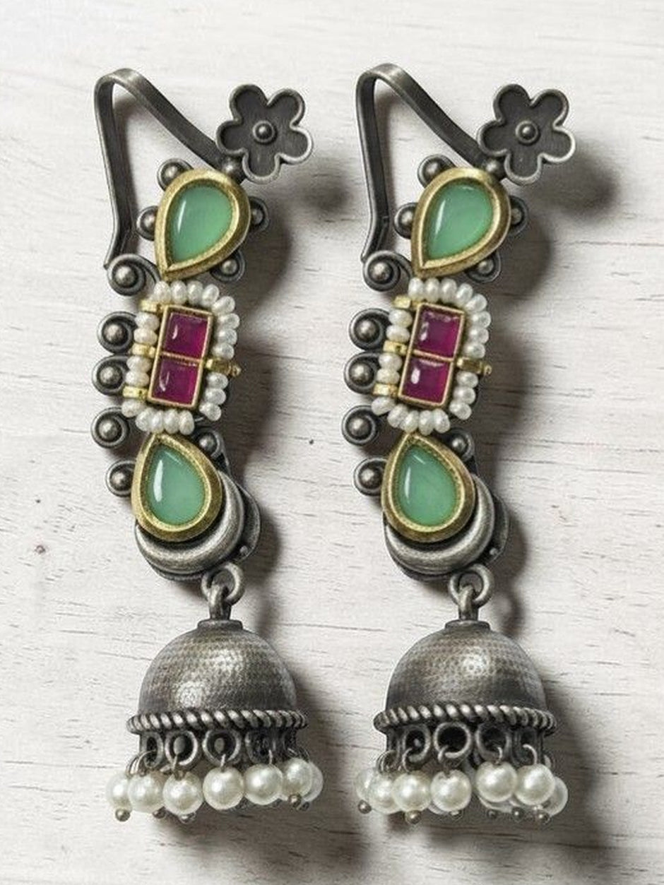 Pair of oxidised silver kundan jhumka earrings with mint-green teardrops and pearl drops on a white wooden surface