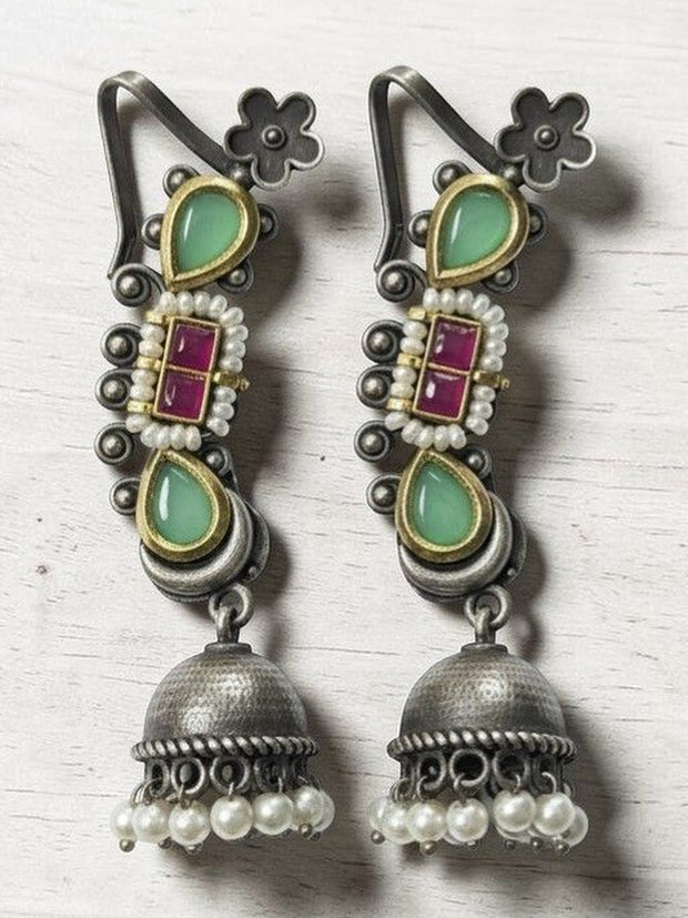 Pair of oxidised silver kundan jhumka earrings with mint-green teardrops and pearl drops on a white wooden surface