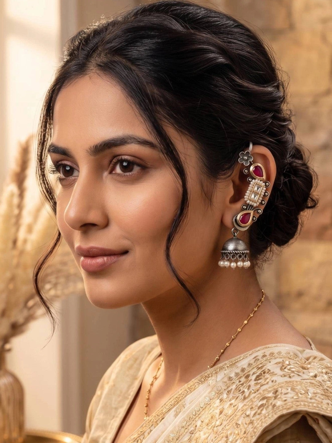Woman wearing oxidised Kundan ear cuff jhumka with an updo and cream embroidered saree in a side profile view