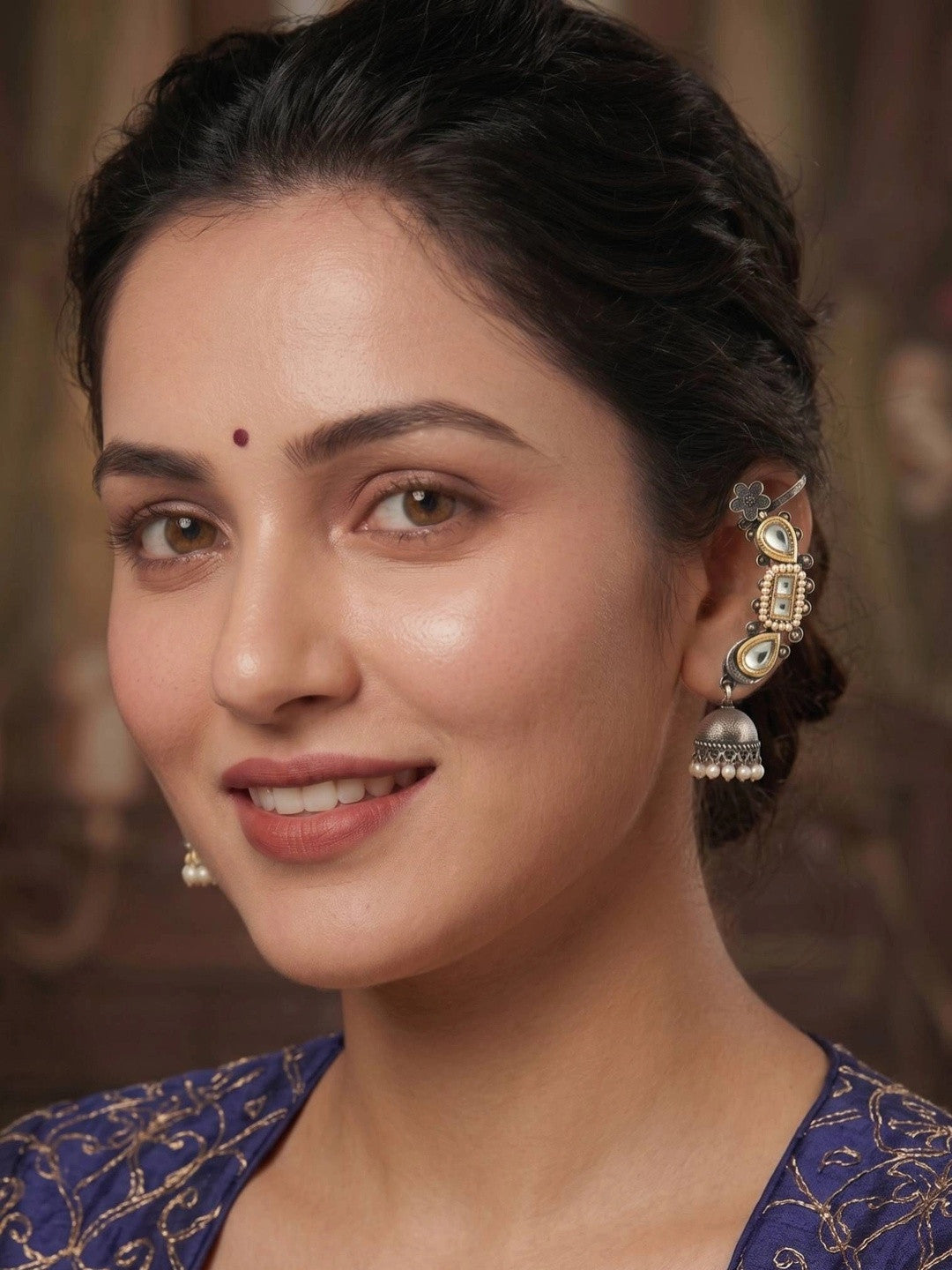 Woman wearing oxidised kundan ear cuff jhumka earring with a blue embroidered outfit and maroon bindi